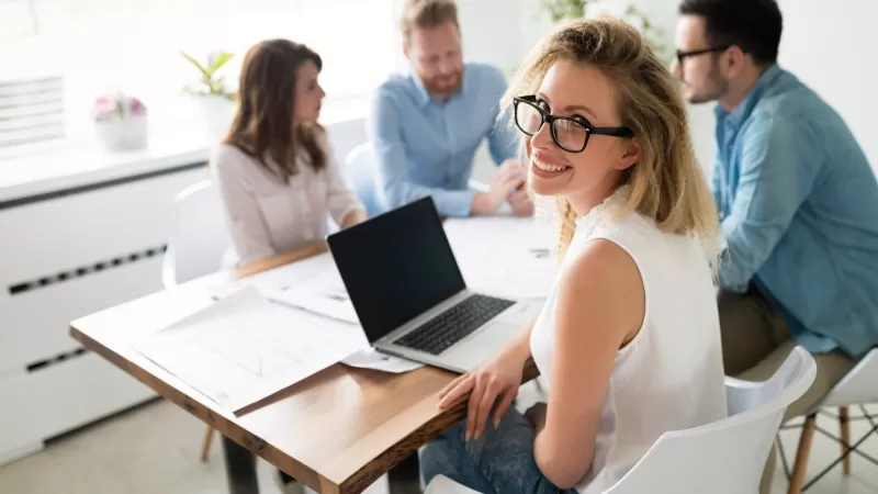 Staff working on a collaborative project with a woman smiling at the camera