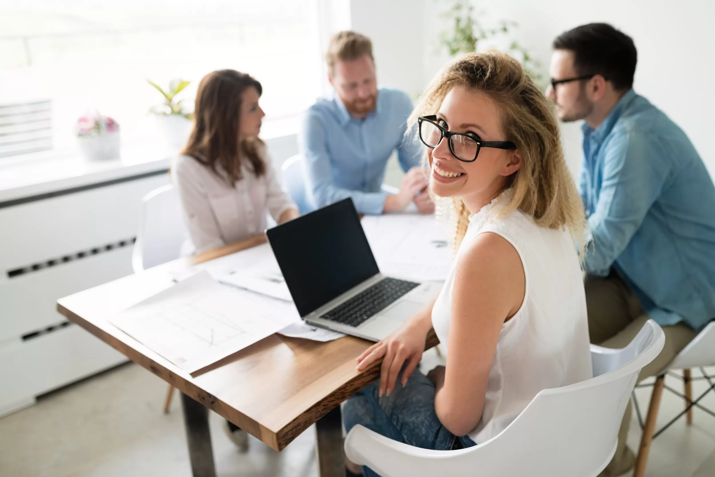 Staff working on a collaborative project with a woman smiling at the camera